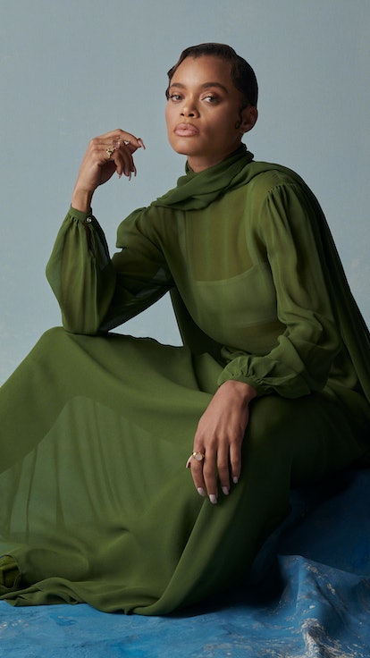 Andra Day posing in a sheer green maxi dress
