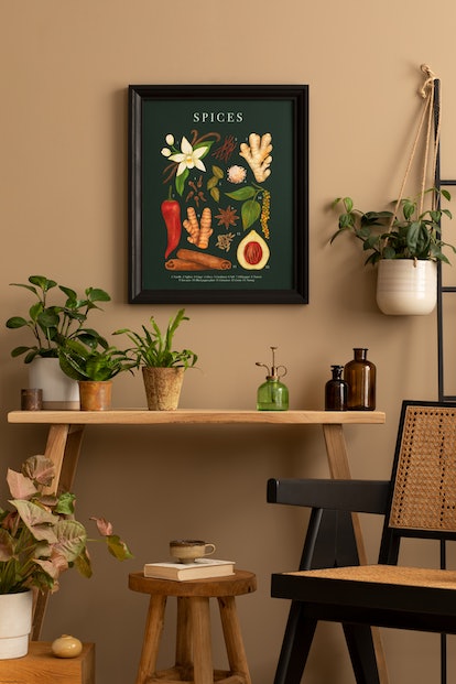 Cozy composition of living room interior with mock up poster frame, plants in flowerpots, rattan arm...